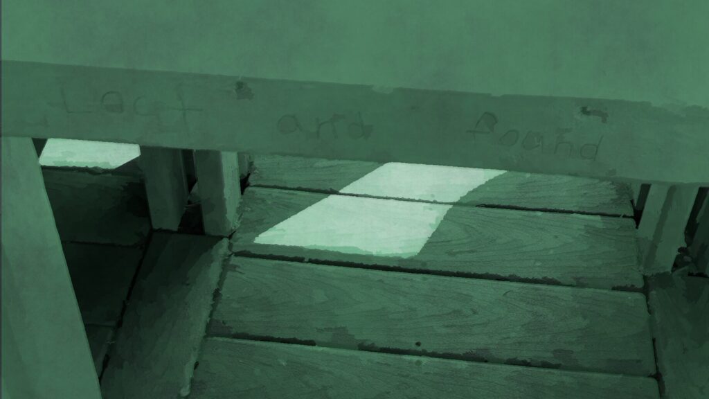The words "lost and found" are carved by a kid into the wood of a playground.